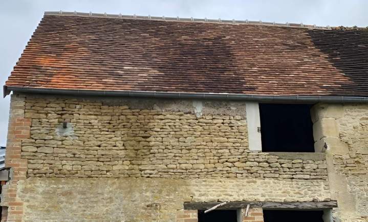 Bâtiment ancien en pierre avec tuiles brun-rouge vieillies Argentan